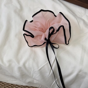 Sweet pink mesh scrunchie with black lace trim and bow on soft white fabric background