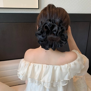 Detail of a large black satin scrunchie styled in a professional updo hairstyle