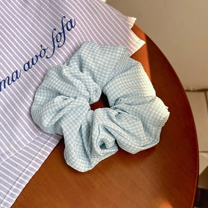 Dettaglio dell'elastico a quadretti azzurro con trama in cotone pieghettato su legno