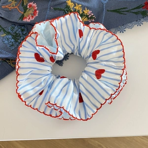 Détail d'un chouchou à rayures bleues avec broderie cœur rouge et bords festonnés