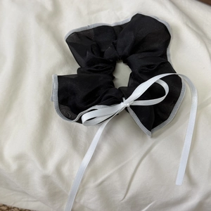 Detail of black mesh hair scrunchie featuring a white satin bow and long streamers