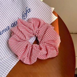 Dettaglio di elastico per capelli a quadretti rossi e bianchi su tavolo di legno