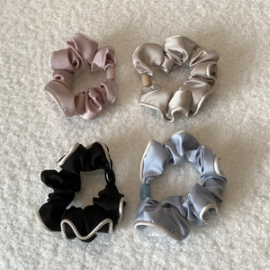 Set of four satin scrunchies in pink, champagne, black, and blue with contrast piping edges