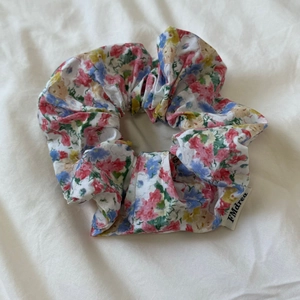 Close-up detail of oil painting style pink floral fabric scrunchie with FMdrea brand label