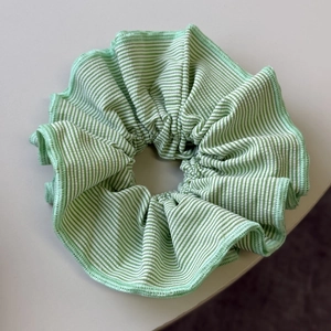 Macro shot of green and white striped cotton scrunchie with detailed overlock edge stitching
