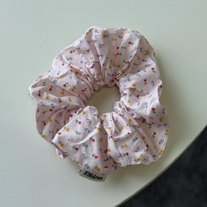 Close-up of pink floral scrunchie with colorful flower patterns and FMdrea woven label