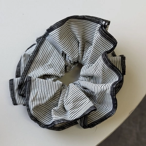 Close-up detail of black and white striped fabric scrunchie with fine stitched edges