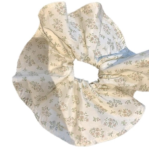 Floral print scrunchie with creamy white fabric and delicate green and pink flower patterns