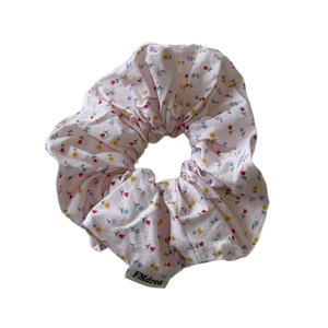 Pastel pink floral scrunchie with colorful flower patterns and woven FMdrea brand label