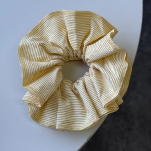 Macro detail of yellow and white striped fabric scrunchie with pleated cotton texture