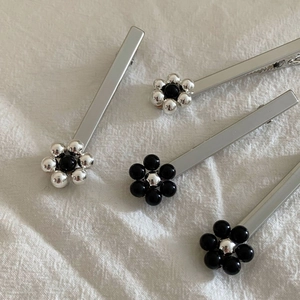 Ensemble de barrettes à fleurs argentées minimalistes avec perles sur fond en tissu blanc