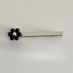 Détail de la pince à cheveux fleur argentée avec pétales noirs et dents dentelées antidérapantes