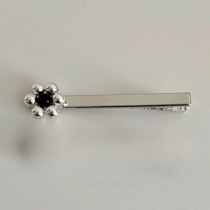 Détail de la barrette à fleurs en métal argenté avec six perles et centre noir perlé