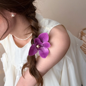 Elegant purple magnolia hair clip styled on a side braid for a graceful floral look