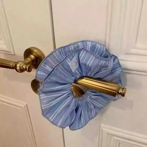 Vacation style light blue striped fabric scrunchie on a vintage gold handle