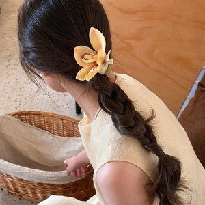 Elegant magnolia flower hair clip with pearl detail worn on a braided hairstyle