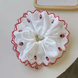White scrunchie with strawberry embroidery and red wavy edges in a cozy layout