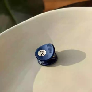 Detail view of mini dark blue acetate hair claw with white number 2 billiard design