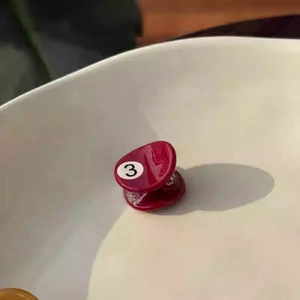 Detail of a mini red glossy pool ball hair claw clip with number 3 design element