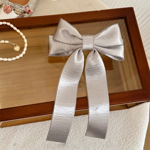 Elegant silver grey satin double bow hair clip with long ribbons on a decorative tray