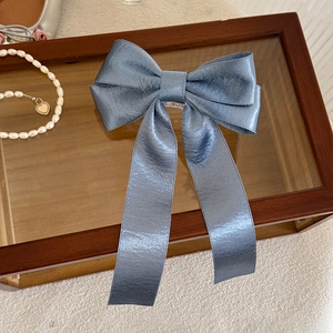 Detail of elegant foggy blue satin hair clip with long ribbons on a decorative tray