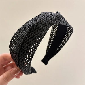 Close-up of the black woven raffia texture and knot detail on the wide headband accessory