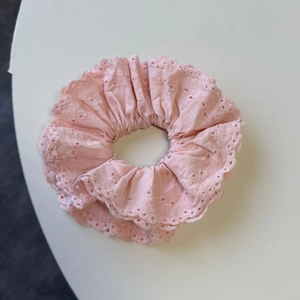 Detail of light pink lace scrunchie with intricate eyelet embroidery and soft pleats