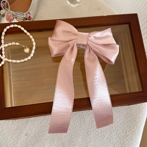 Detailed view of pink satin bow hair clip with long ribbons and premium silk texture