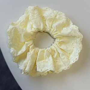 Detailed macro view of pale yellow cotton scrunchie featuring elegant eyelet embroidery