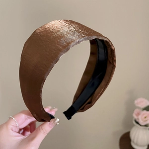 Close-up of a wide brown satin headband showing shiny silk texture and non-slip lining