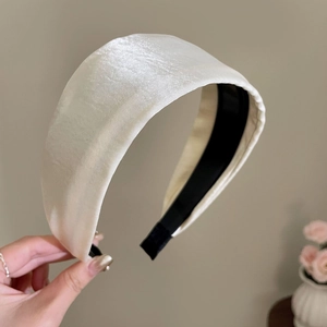 Detailed macro view of cream satin fabric texture and black non-slip inner band on headband