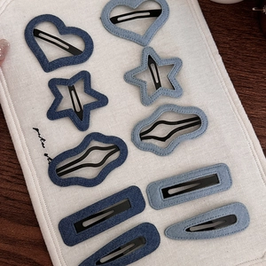 Blue denim fabric hair clip set with heart and star shapes on a white textured board