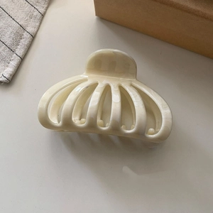 Detailed macro view of retro shell patterned claw clip in cream marble acetate finish