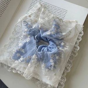 Elastico per capelli a quadretti blu con ricamo in pizzo bianco su libro vintage