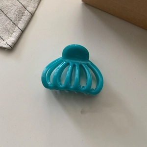 Detail view of the sleek teal resin shark hair claw clip on a stylish neutral desk setup