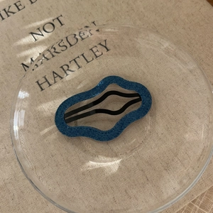 Detail of a wavy blue hair clip with denim texture on a beige fabric background