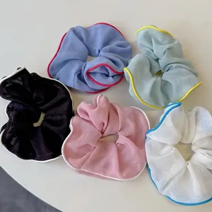 Fünf bunte Mesh-Haargummis mit Kontrastkanten auf einem grauen Tisch präsentiert