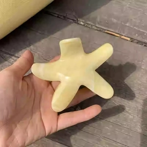 Détail d'une pince à cheveux étoile de mer jaune crème avec texture marbrée en main