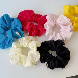 Set of six colorful fabric scrunchies in cotton texture with woven brand tags