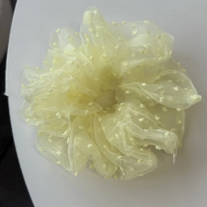 Détail d'un chouchou en organza jaune clair avec pois doux et texture légère