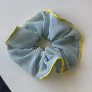 Blaues Mesh-Haargummi mit gelber Paspelierung im sanften, minimalistischen Stil