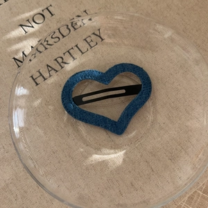 Detailed macro view of heart-shaped blue denim fabric hair clip with black metal BB base