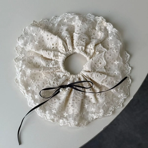 Detailed close-up of cream lace scrunchie with embroidery and pearl bow accent