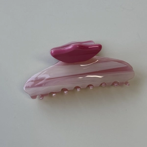 Detailansicht der Haarspange aus Acetat mit rosa-weißem Marmormuster und rotem Griff