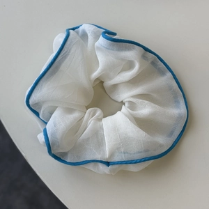 Detail eines weißen Netz-Scrunchie mit blauem Saum und strukturierter Faltenoptik