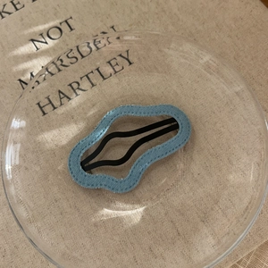 Detail of light blue denim fabric hair clip with stitching on black metal BB clip base