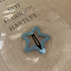Detail view of light blue star hair clip with fabric texture and metal duckbill clip back