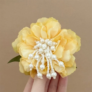Detail of handmade yellow chiffon flower hair clip with delicate pearl stamen accents
