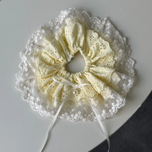 Detailed close-up of lace scrunchie with yellow floral embroidery and pearl ribbon bow