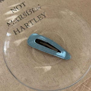 Detail of sky blue satin fabric hair clip with a sleek teardrop-shaped metal base